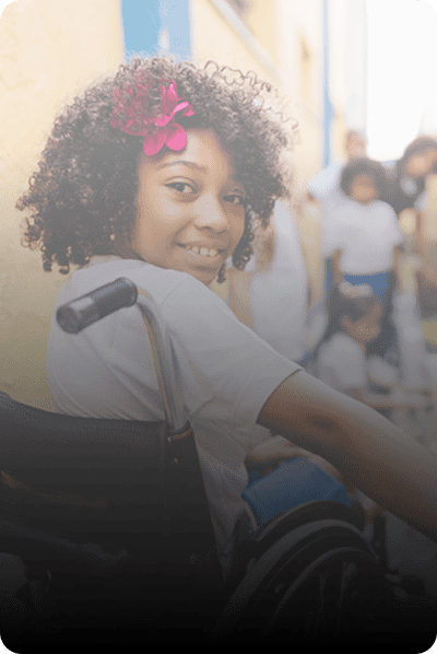 A child in a wheelchair smiling back at the camera